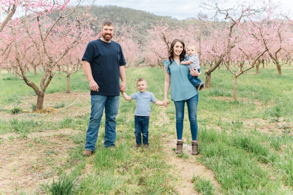 young family standing in spring blossoms at Brosi Sugar Tree Farms in Windston, Oregon. 