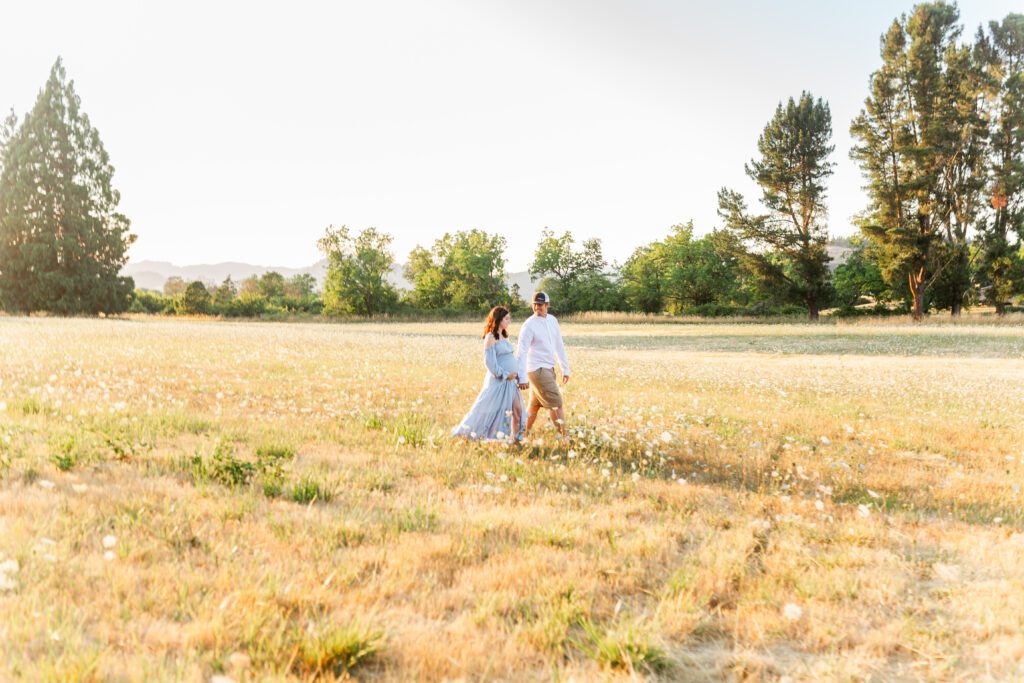 couple walking in roseburg field for maternity photos