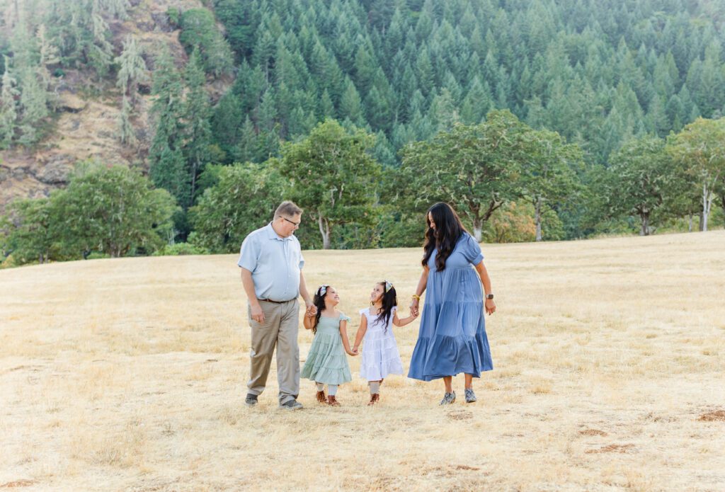 family walking in an open field in Roseburg, Oregon smiling and laughing during family photos