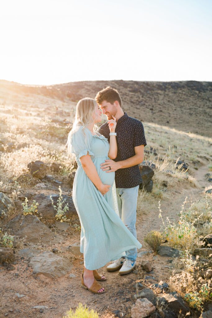 Couple posing for maternity photos in St. George Utah with lava rocks in the background