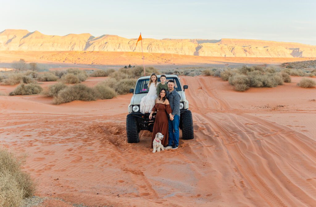 family posing with their off roading vehicle at sand hollow state park in the sand dunes